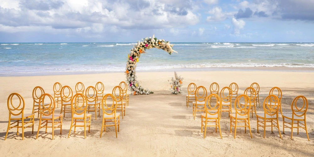 Beachfront wedding ceremony setup with floral arch at Indigo Beach Venue in Zoetry Agua Punta Cana