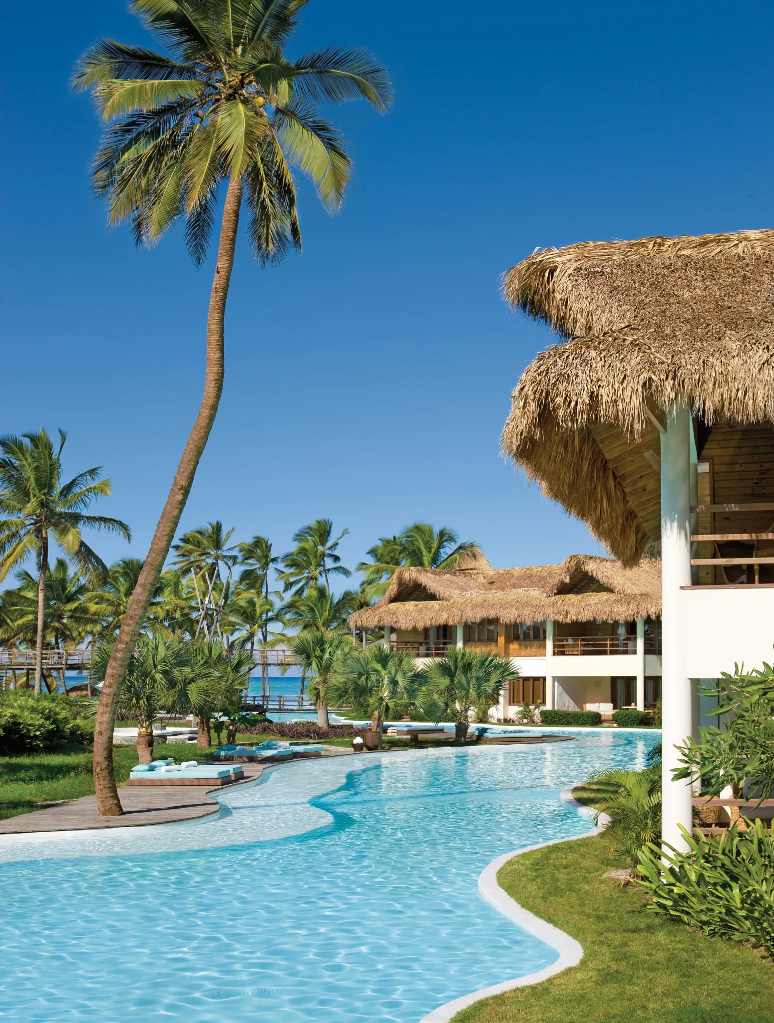 Wide panoramic view of Zoëtry Agua Punta Cana with thatched-roof suites and tropical gardens.