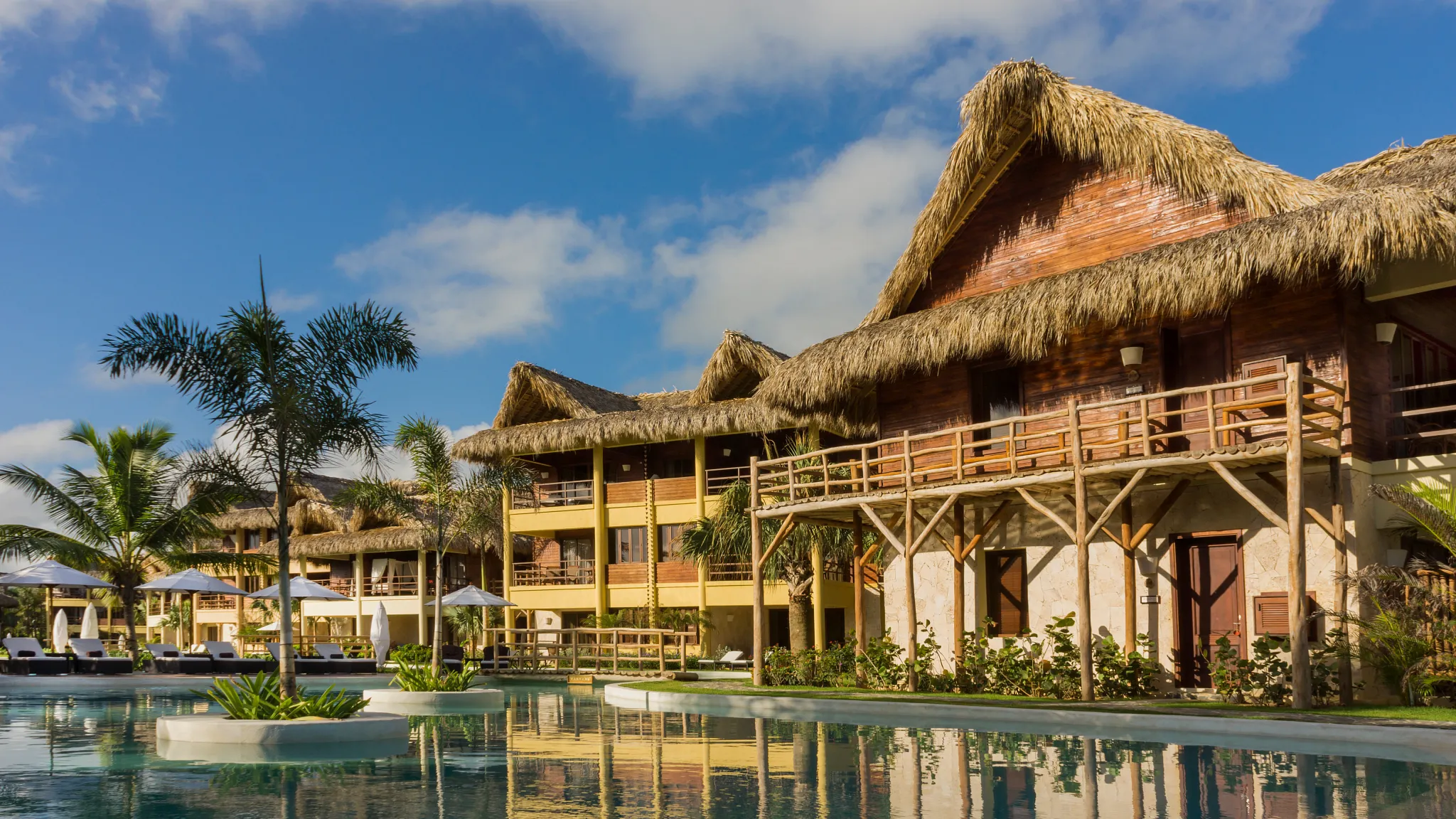 Caribbean-style building with thatched roof overlooking pool at Zoëtry Agua Punta Cana.